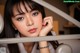 A woman with long black hair and bangs leaning against a railing.