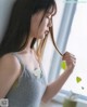 A woman in a gray tank top holding a green leaf.