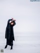 A woman standing in the snow with her arms outstretched.