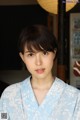 A woman in a blue kimono poses for a picture.