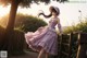 A woman in a purple dress and hat standing on a wooden fence.