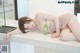 A woman in a pink dress laying on a counter next to a bottle of water.