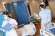 Two nurses in a hospital room with a patient in a bed.