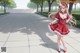 A girl in a red dress and bunny ears is walking down a sidewalk.