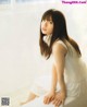 A woman sitting on a window sill in a white dress.