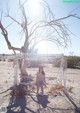 A woman sitting on a swing in the middle of a desert.