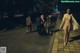 A group of people walking down a sidewalk at night.